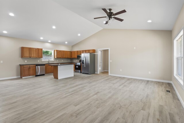 kitchen with light wood-type flooring, stainless steel appliances, vaulted ceiling, ceiling fan, and a center island