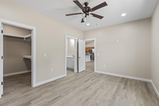 unfurnished bedroom with ceiling fan, light hardwood / wood-style flooring, a spacious closet, connected bathroom, and a closet