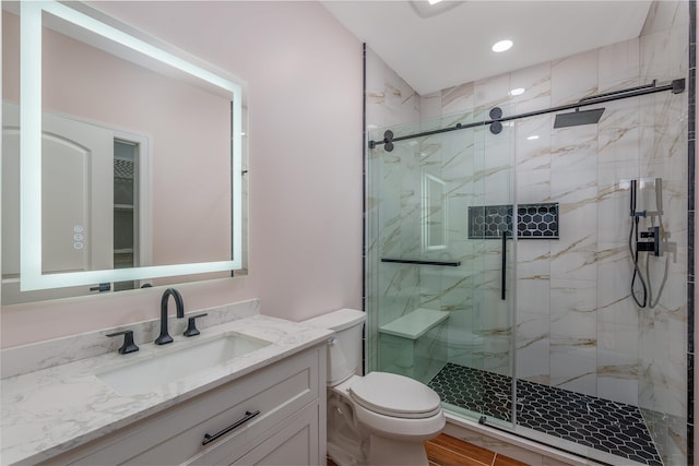 full bath featuring toilet, a marble finish shower, and vanity