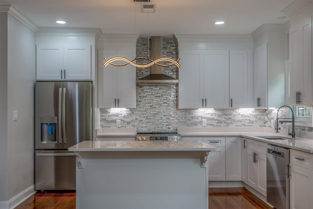 kitchen featuring stainless steel appliances, wall chimney exhaust hood, a sink, white cabinets, and decorative backsplash