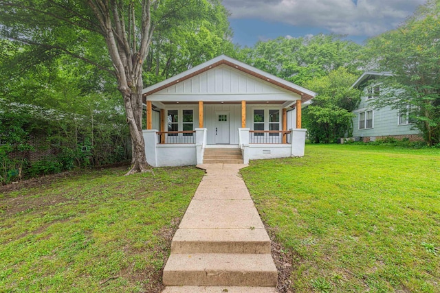 bungalow-style home featuring board and batten siding, covered porch, and a front yard