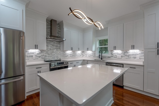 kitchen featuring stainless steel appliances, wall chimney range hood, a sink, dark wood-style floors, and backsplash