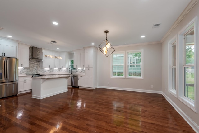 kitchen featuring stainless steel appliances, wall chimney range hood, healthy amount of natural light, crown molding, and recessed lighting