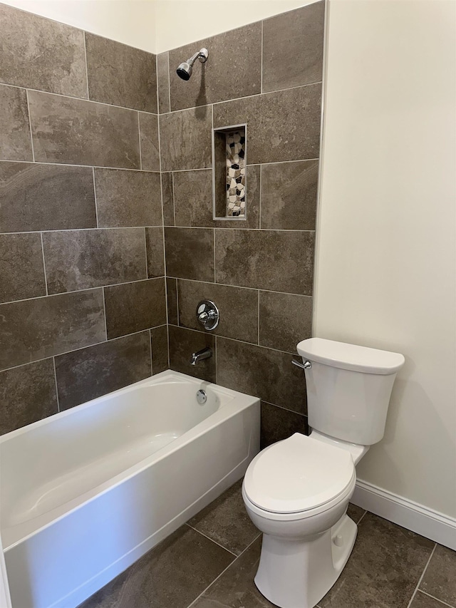 bathroom featuring tile patterned flooring, tiled shower / bath combo, and toilet