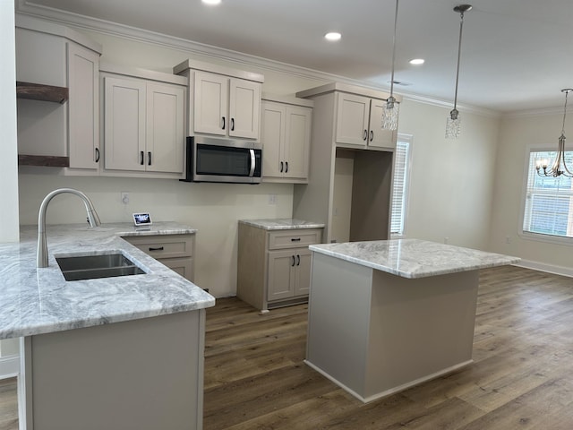 kitchen with light stone counters, hanging light fixtures, a notable chandelier, and sink