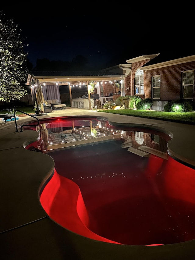 pool at night with a patio area