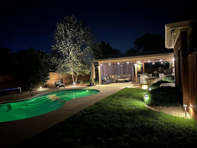 pool at twilight with outdoor lounge area, a patio, and an outdoor kitchen