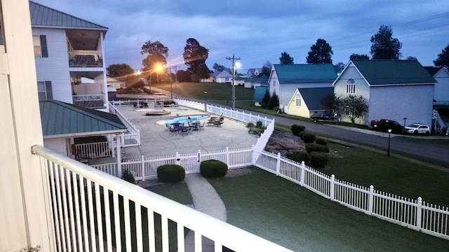 pool at dusk featuring a yard and a patio area