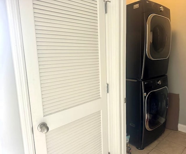 laundry room featuring stacked washer and dryer and light tile patterned floors