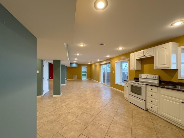 kitchen featuring white cabinets, light tile patterned floors, white range with electric cooktop, and sink