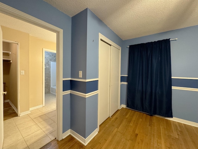 hall featuring light hardwood / wood-style flooring and a textured ceiling