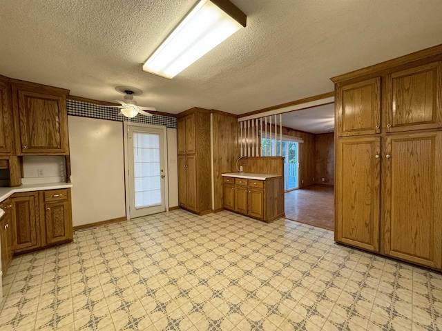 kitchen with ceiling fan, wooden walls, and a textured ceiling