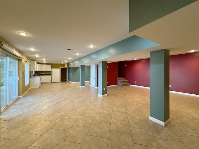 basement featuring white refrigerator and light tile patterned flooring