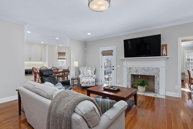 living room featuring crown molding, hardwood / wood-style flooring, and a fireplace