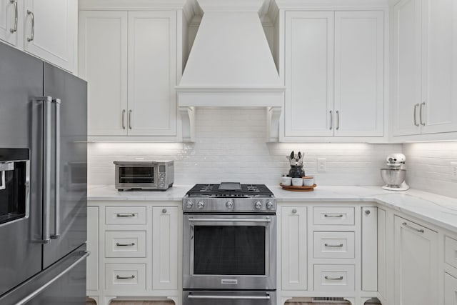 kitchen featuring premium range hood, stainless steel appliances, backsplash, and white cabinets