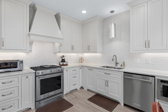 kitchen with stainless steel appliances, custom range hood, sink, and white cabinets