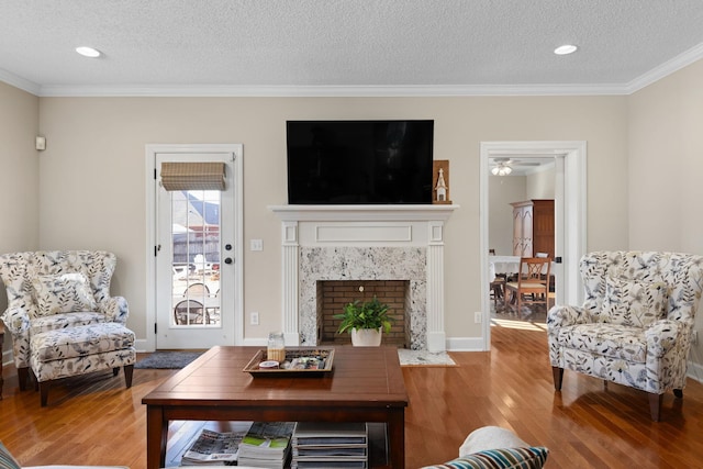 living room with crown molding, wood-type flooring, a fireplace, and a textured ceiling