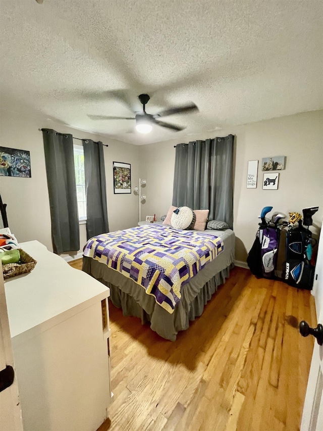 bedroom with a textured ceiling, light wood-style floors, and ceiling fan