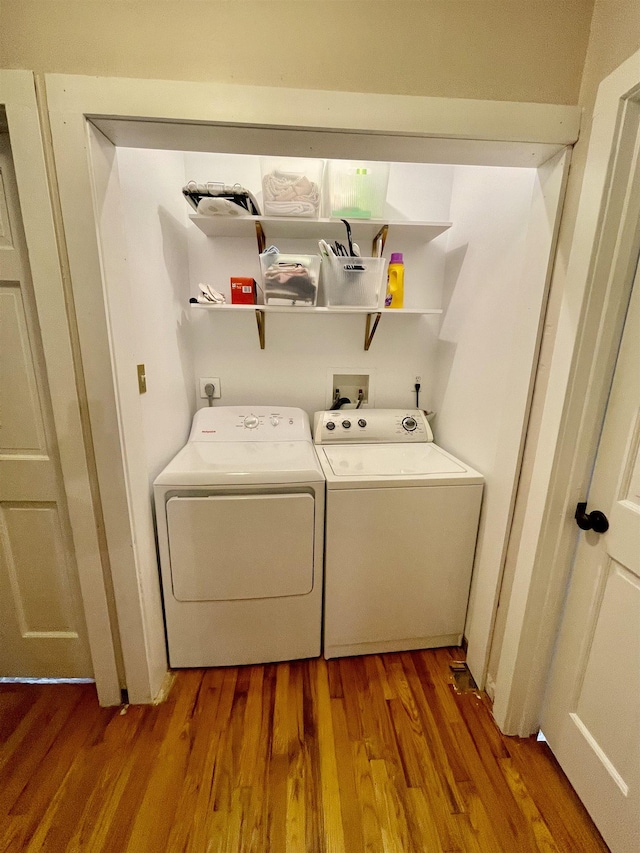 clothes washing area featuring separate washer and dryer and wood finished floors
