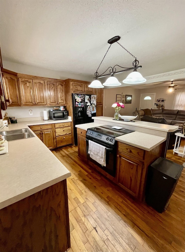 kitchen with black appliances, a sink, light countertops, and light wood finished floors