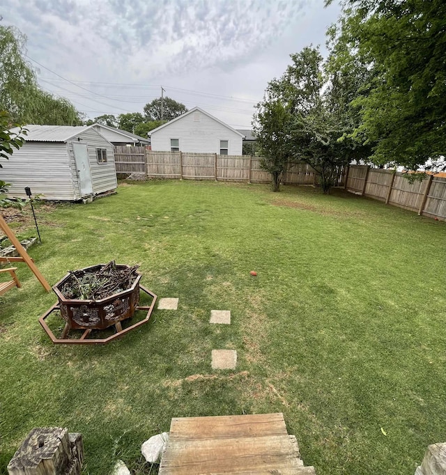 view of yard with an outdoor fire pit, an outdoor structure, and a storage unit