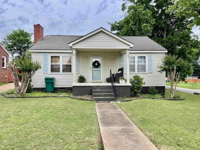 bungalow-style home featuring a shingled roof, a front yard, crawl space, and a chimney