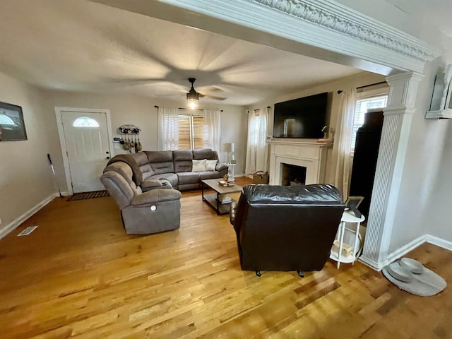 living area featuring a fireplace, baseboards, wood finished floors, and healthy amount of natural light