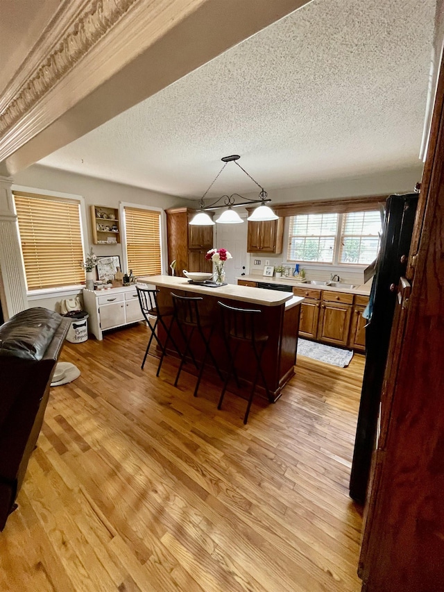 kitchen with light countertops, light wood finished floors, a kitchen island, a breakfast bar area, and a textured ceiling
