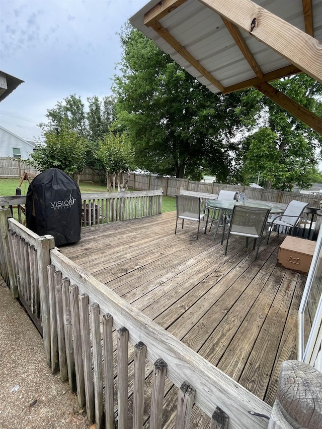 deck featuring outdoor dining area, a grill, and a fenced backyard