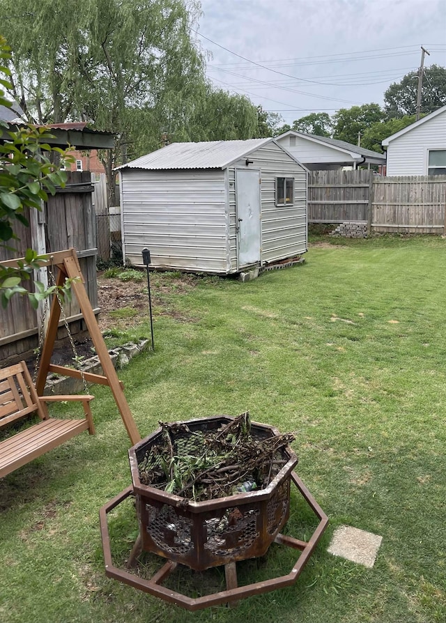 view of yard featuring a storage unit, an outdoor structure, and an outdoor fire pit