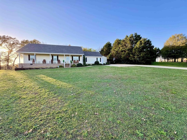 ranch-style home featuring covered porch and a front lawn