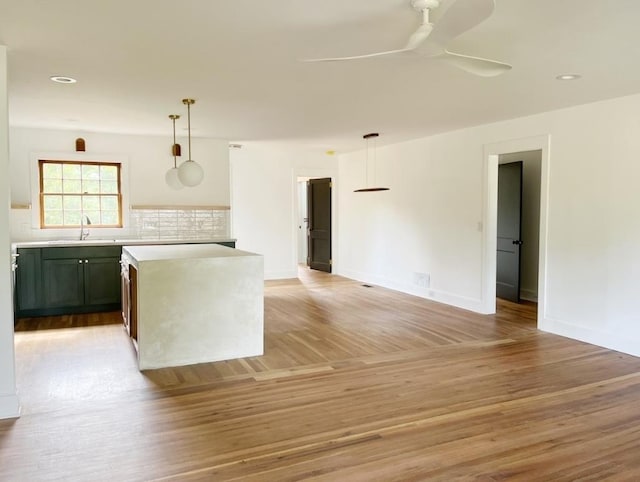 kitchen with light wood-style floors, light countertops, and hanging light fixtures