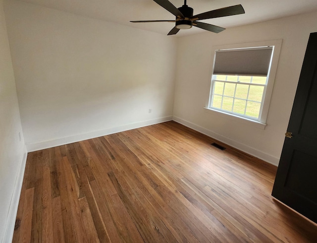 unfurnished room with visible vents, ceiling fan, baseboards, and wood finished floors