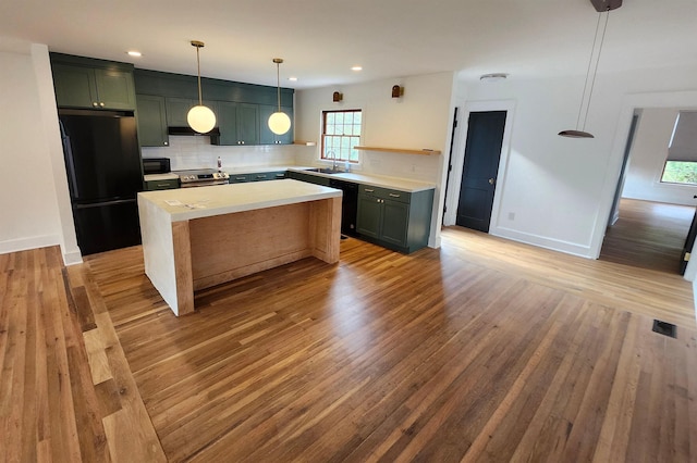 kitchen with light countertops, hanging light fixtures, backsplash, a sink, and black appliances