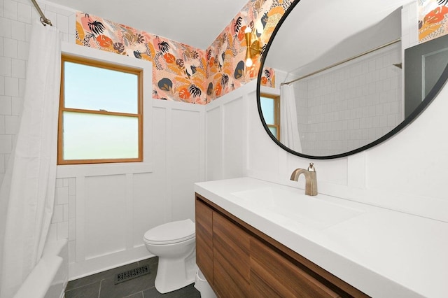 full bath with toilet, a decorative wall, visible vents, wainscoting, and wallpapered walls