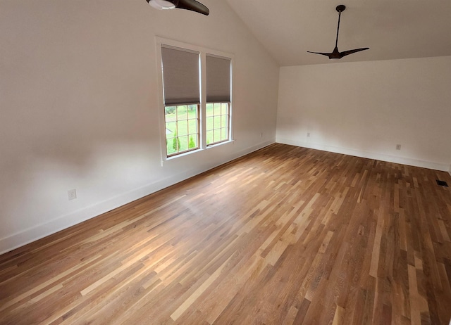 empty room with a ceiling fan, baseboards, vaulted ceiling, and light wood finished floors