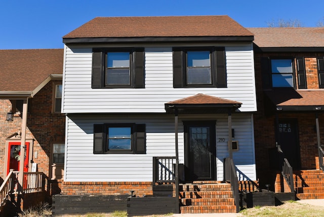 view of front of house with brick siding and a shingled roof