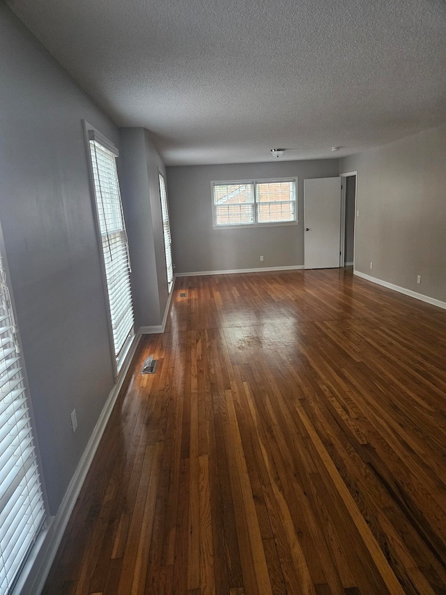 spare room featuring dark hardwood / wood-style flooring and a textured ceiling