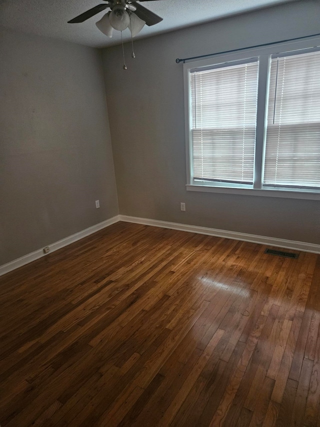 unfurnished room featuring a textured ceiling, ceiling fan, and dark wood-type flooring