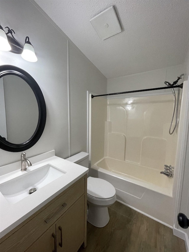 full bathroom with shower / bathtub combination, vanity, a textured ceiling, hardwood / wood-style floors, and toilet