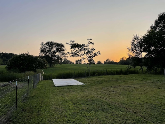 yard at dusk featuring a rural view