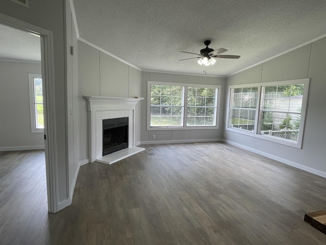 unfurnished living room featuring ceiling fan, dark hardwood / wood-style floors, crown molding, vaulted ceiling, and a tiled fireplace