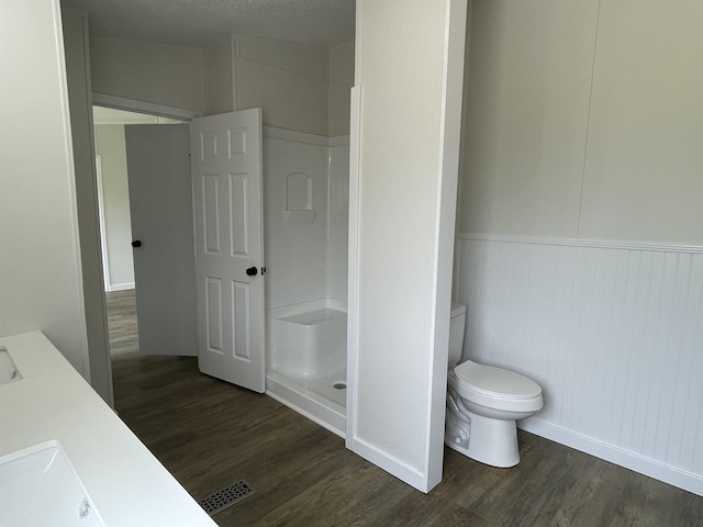 bathroom featuring vanity, toilet, a textured ceiling, walk in shower, and wood-type flooring