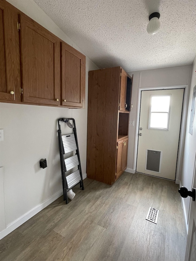 laundry area featuring a textured ceiling and light hardwood / wood-style flooring