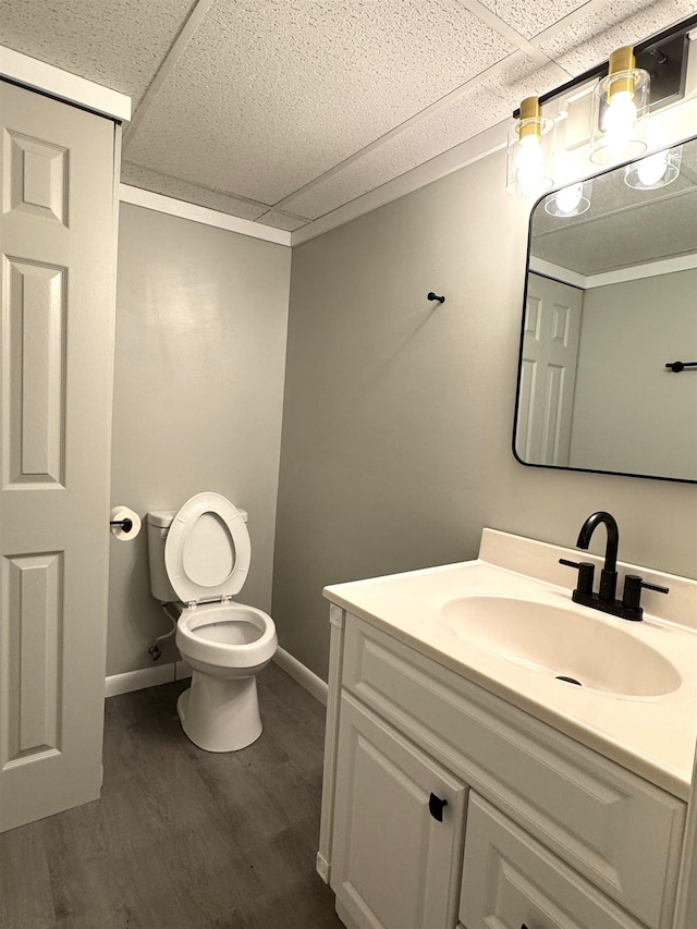 bathroom featuring vanity, toilet, wood-type flooring, and a drop ceiling