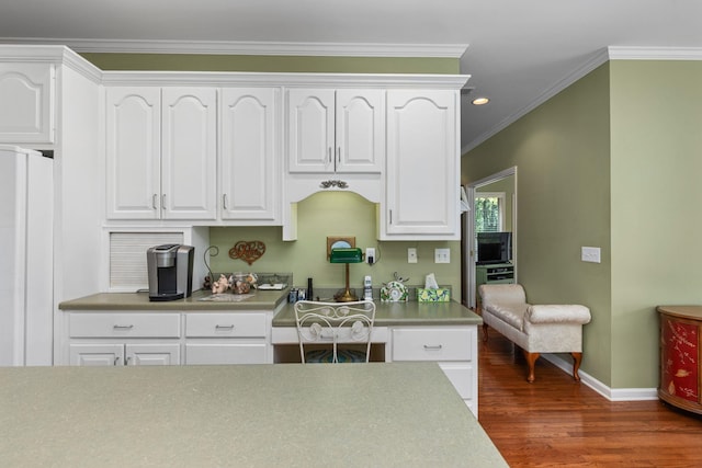  - kitchen with wood finished floors, baseboards, white cabinets, freestanding refrigerator, and ornamental molding