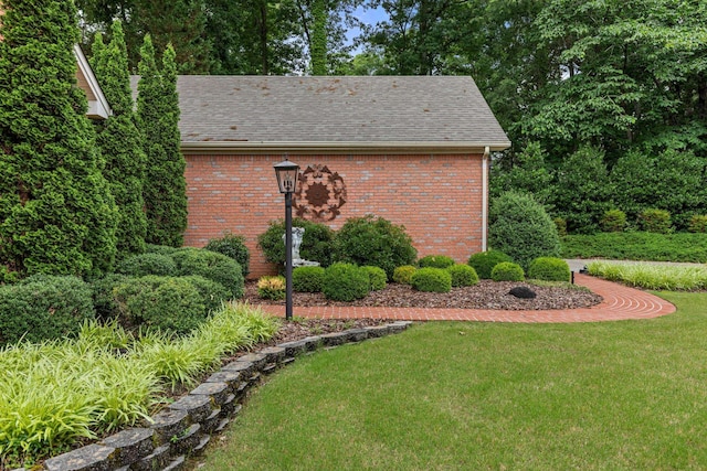 - view of side of property featuring brick siding, a yard, and roof with shingles