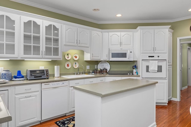  - kitchen with white appliances, a sink, white cabinets, wood finished floors, and crown molding
