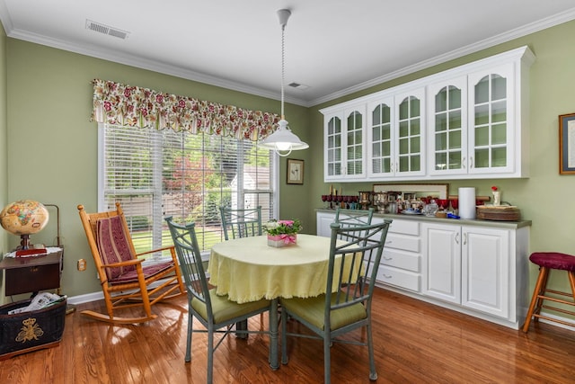  - dining space with wood finished floors, ornamental molding, and baseboards