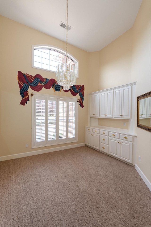  - unfurnished dining area featuring high vaulted ceiling, a chandelier, and light colored carpet